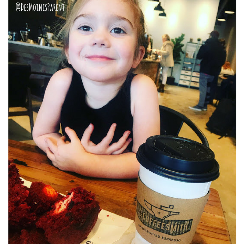 Little girl sitting at table with take-out coffee cup and muffin.
